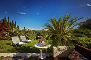 un patio con 2 sedie, un tavolo e una palma di Villa Archi B&B a San Pietro in Cariano