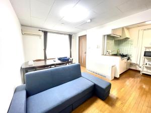 uma sala de estar com um sofá azul e uma cozinha em Avidasion - Vacation STAY 12208 em Biei