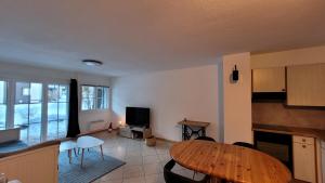 a living room with a wooden table and a kitchen at Appartement avec terrasse ensoleillée in Gruyères