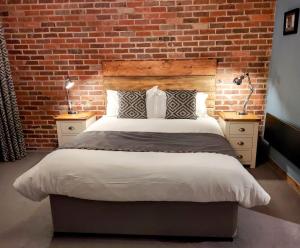 a bedroom with a large bed with a brick wall at Trawden Arms Community Owned Pub in Winewall