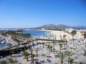 Blick auf einen Strand mit Palmen und einer Brücke in der Unterkunft Tranquilo apartamento con vistas al mar. in Port d'Alcúdia