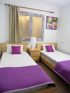 2 Betten in einem Zimmer mit lila Bettwäsche in der Unterkunft Tranquilo apartamento con vistas al mar. in Port d'Alcúdia + 37 Fotos