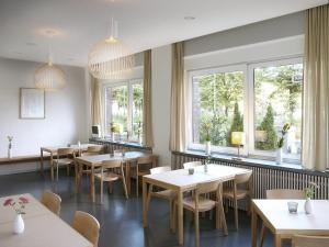 a restaurant with tables and chairs and windows at ART Hotel Ufer in Düsseldorf