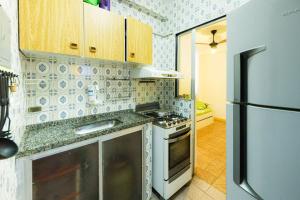 a kitchen with a stove and a refrigerator at Apart a 450 metros da Praia de Ponta Negra RJ in Jaconé