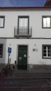 Edificio blanco con puerta verde y balcón en Old Évora Hostel, en Évora