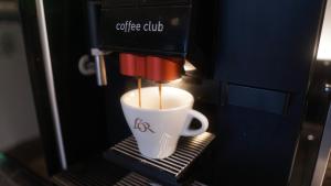 eine Kaffeetasse wird in einer Kaffeemaschine gebraut in der Unterkunft Hotel JeštěBrno in Brünn