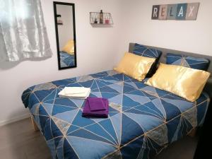 a bedroom with a bed with a blue and gold bedspread at Charmant appartement T2 dans villa avec en supplément spa extérieur de mai à septembre in Laveyron