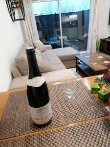 a bottle of wine sitting on a table in a living room at Charmant appartement T2 dans villa avec en supplément spa extérieur de mai à septembre in Laveyron