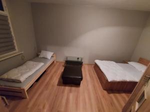 two beds in a small room with wooden floors at Spalona Apartament Jagodna in Bystrzyca Kłodzka