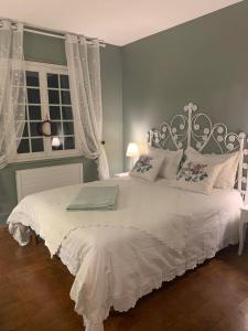 Un dormitorio con una cama blanca con sábanas blancas y una ventana en La Villa de Lise, en Romans-sur-Isère