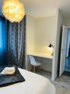 a bedroom with a bed and a desk and a chandelier at Superbe T3 proche de l'hypercentre de Lorient avec terrasse in Lorient