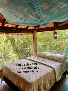 a bedroom with a bed in front of a window at Casa Cabana Ecológica in Boicucanga