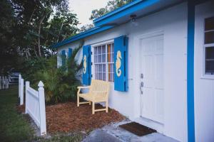 a blue and white house with a chair next to a door at Charming home with hot tub, minutes from the beach in Vero Beach