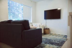uma sala de estar com um sofá e uma televisão de ecrã plano em Charming home with hot tub, minutes from the beach em Vero Beach
