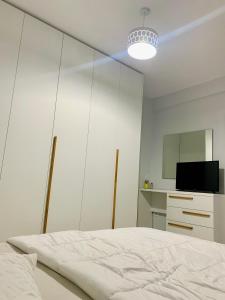 um quarto branco com uma cama e uma televisão em Lovely Apartment at the city of Tirana em Tirana