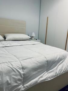uma grande cama branca com um cobertor branco em Lovely Apartment at the city of Tirana em Tirana