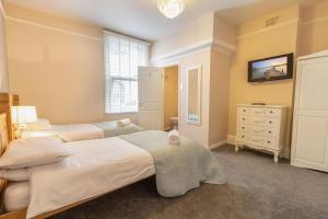 a bedroom with two beds and a dresser and a window at Sunnymead in Torquay