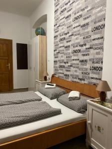 two beds in a room with a wall with words at Anna Apartman in Pápa