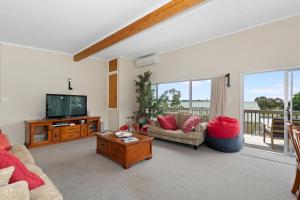 a living room with a tv and a couch and a table at Tahuna Family Escape - Paihia Holiday Home in Paihia