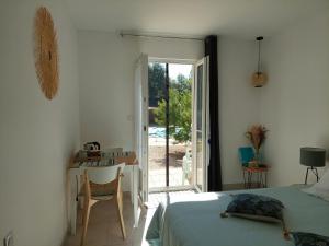 Saint-DidierにあるMaison d'Hôtes & Spa La Chêneraie-Provence Ventouxのベッドと机と窓のある寝室