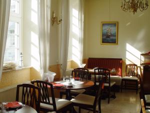 a dining room with tables and chairs and windows at Hotel Altes Hafenhaus in Rostock