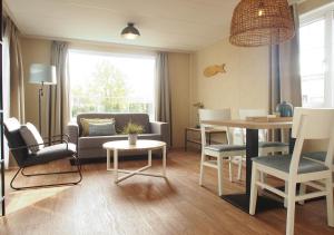 a living room with a couch and a table at Chaletparc Krabbenkreek Zeeland - Chalet 152 in Sint Annaland