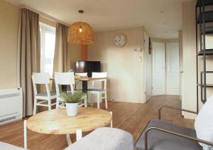 a living room with a table and chairs and a clock at Chaletparc Krabbenkreek Zeeland - Chalet 152 in Sint Annaland