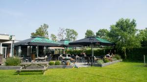 a patio with tables and chairs and umbrellas at Chaletparc Krabbenkreek Zeeland - Chalet 152 in Sint Annaland