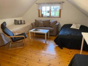 a bedroom with a bed and a couch and a table at Central vindslägenhet med gratis parkering in Lindesberg