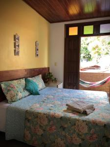 1 dormitorio con 1 cama con edredón azul y ventana en Pousada Morro Bello, en Morro de São Paulo