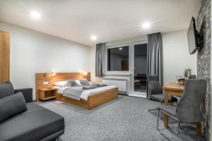 1 dormitorio con cama, escritorio y sofá en Apartmány Sendy en Ždiar