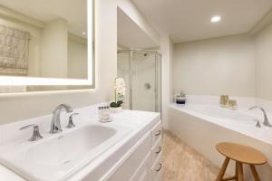 a white bathroom with two sinks and a shower at Pacific Edge Hotel in Laguna Beach