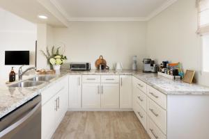 a kitchen with white cabinets and marble counter tops at Pacific Edge Hotel in Laguna Beach