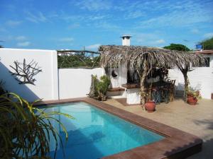 a house with a swimming pool and a thatch roof at Casa Playas in Playas