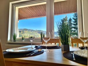 a table with two wine glasses and a window at Apartamenty Willa NaSkarpie Jacuzzi Sauna Basen in Wisła