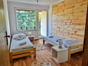 two beds in a room with a wooden wall at Apartamenty Willa NaSkarpie Jacuzzi Sauna Basen in Wisła +38 photos