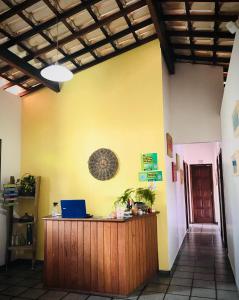 a lobby with a desk with a laptop on a yellow wall at Pousada Morro Bello in Morro de São Paulo