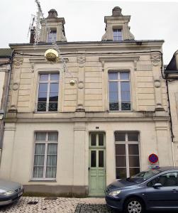 un edificio con una puerta verde y un reloj en él en Le Lude Land Musée, en Le Lude