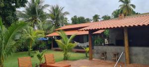 a house with a patio with chairs and palm trees at Recanto Ubuntu in Japaratinga