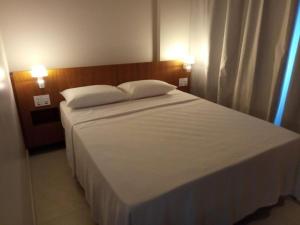 um quarto com uma grande cama branca e 2 almofadas em Salinas Exclusive Resort 24 em Salinópolis