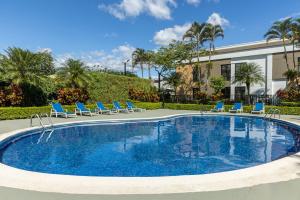 a swimming pool with blue chairs and a building at Holiday Inn Express San Jose Costa Rica Airport by IHG in Alajuela City