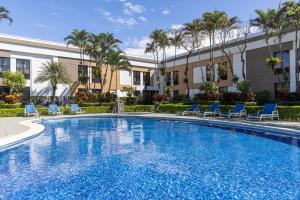 a swimming pool with chairs and a building at Holiday Inn Express San Jose Costa Rica Airport by IHG in Alajuela City
