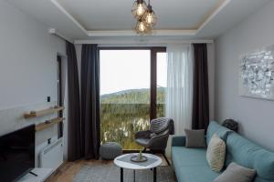 ein Wohnzimmer mit einer blauen Couch und einem großen Fenster in der Unterkunft Vila Planinsko Blago in Kopaonik