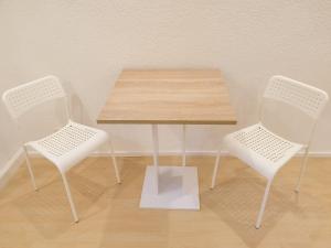 a table with two white chairs and a wooden table at 2 Zimmer Apartment im UG Schelklingen Biosphärenreservat Schwäbische Alb in Schelklingen