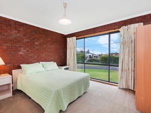 a bedroom with a bed and a brick wall at Ambience By The Sea in Port Fairy