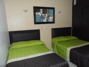 zwei Betten in einem Zimmer mit grünen Laken in der Unterkunft Hotel Fernando in Tuxtla Gutiérrez