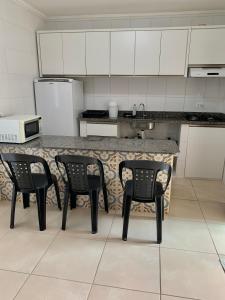 a kitchen with a counter with four chairs around it at Residencial L & L in Guaratuba