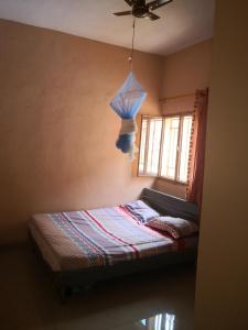 a bedroom with a bed with a ceiling fan and a window at Résidence Les Fleurettes in Bamako