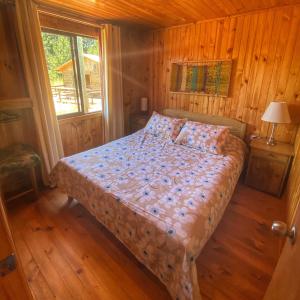 - une chambre avec un lit dans une cabane en bois dans l'établissement Cabañas Refugio Las Conejas, à Pelluhue