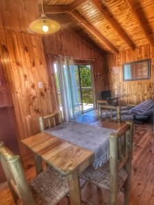 uma sala de jantar com uma mesa de madeira e cadeiras em Cabañas Refugio Las Conejas em Pelluhue